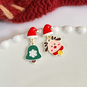 Asymmetric Christmas earrings featuring Santa hat, bell, and reindeer on a white plate