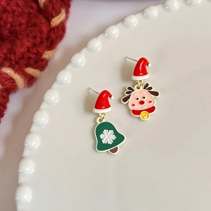 Detail of asymmetrical Christmas earrings with a cute reindeer and a green bell design