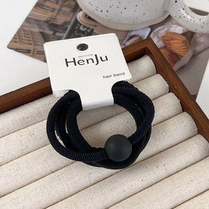 Detail of high-elastic black hair ties with matte round beads on a display card