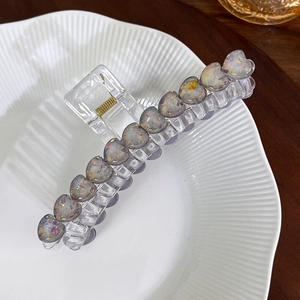 Makro-Detail der großen Acryl-Haarklammer mit schillernden Glitzer-Herzmustern