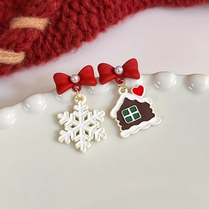 Detail view of asymmetric Christmas stud earrings with snowflake and gingerbread house design