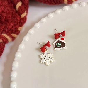 Detail of Christmas earrings featuring gingerbread house, snowflake, and red bow accents