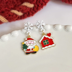 Detail of asymmetric Christmas earrings with Santa and heart house on white ceramic