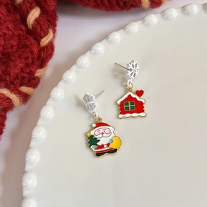 Detail of Christmas earrings with Santa and house charms on a textured white plate