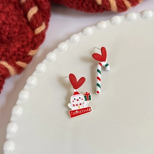 Macro view of asymmetrical Christmas earrings with snowman and candy cane details