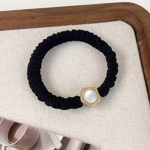 Detailansicht des schwarzen Scrunchies mit goldener Blume und zentraler Perle