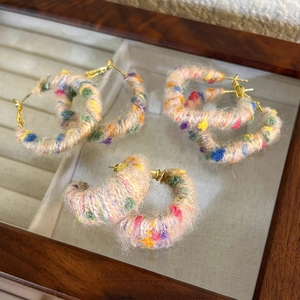 Gros plan détaillé des boucles d'oreilles créoles en laine colorée sur un coffret à bijoux