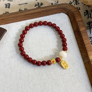 Macro shot of red cinnabar-style beads with gold lucky charm and white jade on a tray