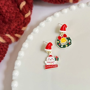 Detail view of asymmetric Christmas wreath and snowman earrings on white ceramic plate