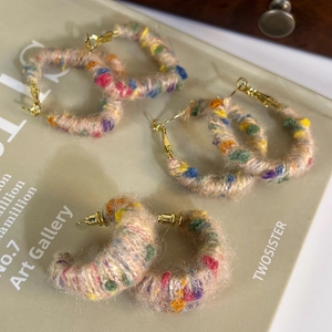 Détail de boucles d'oreilles créoles colorées en laine avec formes rondes et rectangulaires