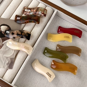 Detail view of ten assorted wavy acetate hair clips with France Handmade gold lettering