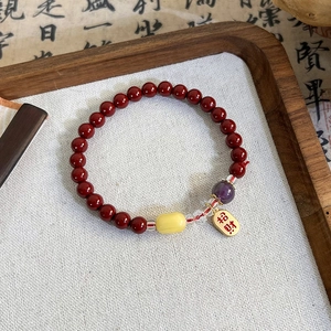Detailed macro view of cinnabar-style red beaded bracelet with a golden fortune charm