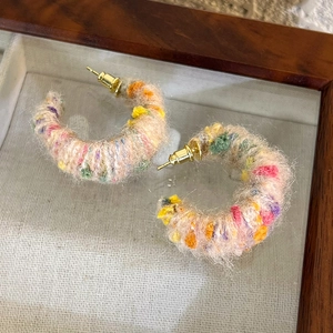 Détail des boucles d'oreilles créoles en peluche colorée avec texture rose douce