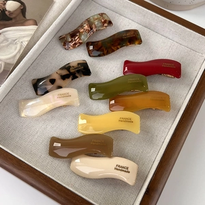 French style handmade wave acetate hair clips in multiple colors on a cream tray