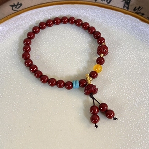 Macro detail of Chinese cinnabar style red beaded bracelet with lotus charms on ceramic plate