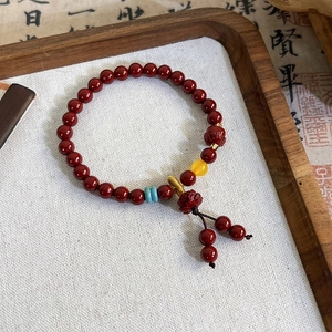 Detailed shot of red cinnabar beaded bracelet with lotus charm on wooden tray