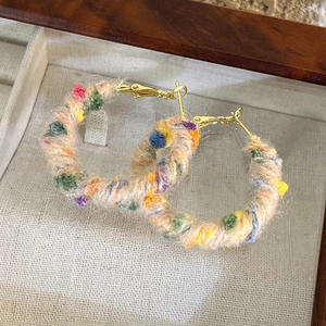 Gros plan de boucles d'oreilles créoles en laine colorée avec crochets dorés