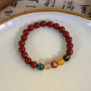 Close-up of red beaded bracelet with engraved lotus and golden mantra charms