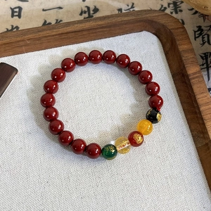 Macro shot of red beaded bracelet with intricate golden character engravings and colorful accents