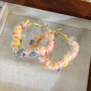 Détail de boucles d'oreilles créoles en peluche colorée avec texture douce en fil de laine