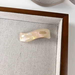 Macro shot of wavy acetate hair clip with pearl luster and gold France Handmade logo