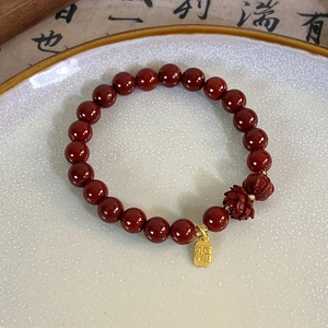 Detailed shot of cinnabar red beads bracelet featuring a carved lotus and gold Fu tag