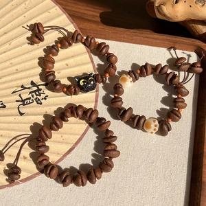 Détail des breloques grains de café avec accents de pattes de chat sur bracelets tissés