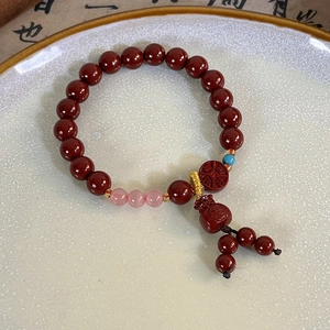 Detailed close-up of a red cinnabar-style beaded bracelet with a symbolic lotus pendant