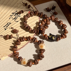 Détail de bracelets en grains de café avec breloques de patte de chat et perles