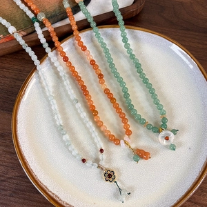 Detail of beaded bracelets featuring enamel flowers and agate charms on ceramic