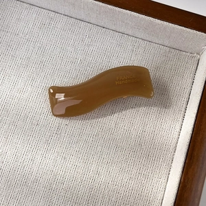 Detail showing wave-shaped brown acetate hair clip with France Handmade engraving