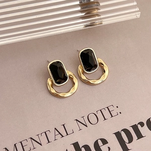 Détail de boucles d'oreilles carrées avec pierre noire et créoles dorées texturées