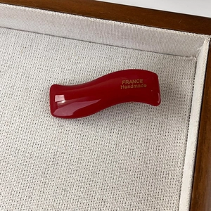 Detail showing red wavy cellulose acetate hair clip with France Handmade gold lettering