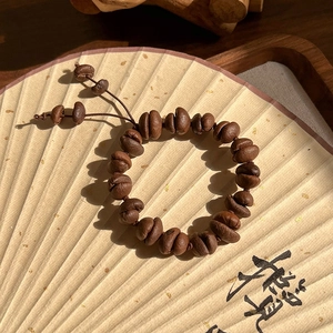 Vue détaillée d'un bracelet de grains de café fait main avec cordon sur un éventail
