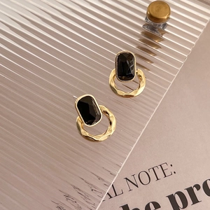 Gros plan détaillé de boucles d'oreilles rétro dorées avec pierres noires géométriques