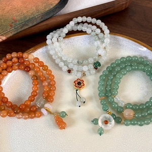 Retro multi-layer floral bracelet with green agate and jade beads on a ceramic tray