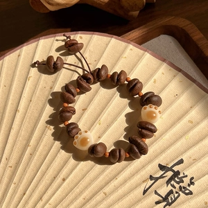 Détail macro d'un bracelet en grains de café avec pattes de chat sur un éventail