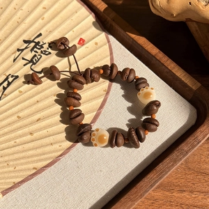 Détail du bracelet en grains de café et patte de chat sur un plateau en bois poli