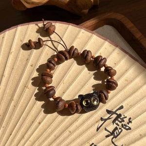 Détail des perles en forme de grain de café et chat sur bracelet tressé brun