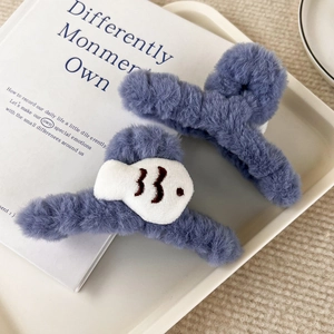 Dettaglio della molletta per capelli in peluche blu con ricamo di un piccolo pesce