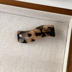 Close-up of tortoise shell pattern acetate wave hair clip with gold handmade lettering