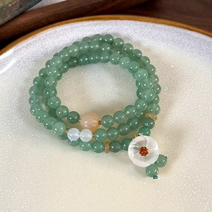 Macro view of multi-layer green agate beads with delicate white flower charm detail