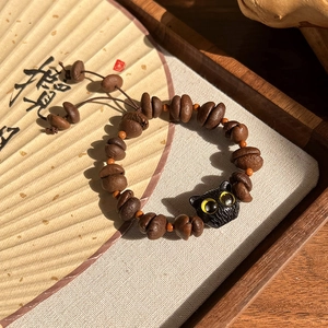 Vue détaillée des perles de grains de café et du charm chat noir sur le bracelet
