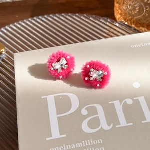 Détail de boucles d'oreilles rose fuchsia en peluche avec papillon en strass et perles