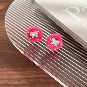 Vue détaillée des boucles d'oreilles en peluche rose avec papillon en cristal