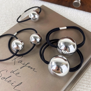Élastiques à cheveux avec boule argentée miroir posés sur un livre décoratif