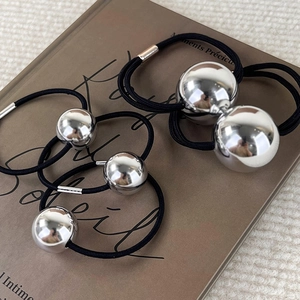 Élastiques à cheveux noirs minimalistes avec boules argentées brillantes sur un livre