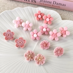 Detailed close-up of pink flocked cherry blossom earrings on a white ceramic display