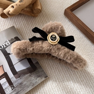 Detail of plush brown faux fur hair claw with black velvet bow and vintage rose badge