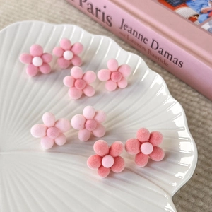 Detailed view of pink flocked flower earrings displayed on a white shell ceramic tray